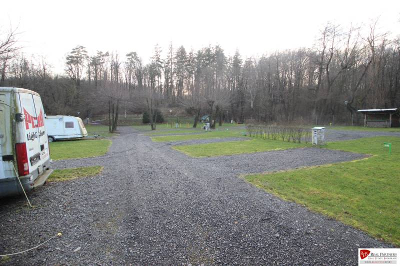 Zabehnutý multifunkčný rekreačný areál (kemp) Kuchyňa na predaj - Rekreačné pozemky v Kuchyni s karavanami, štrkovými cestami a lesným okolím.