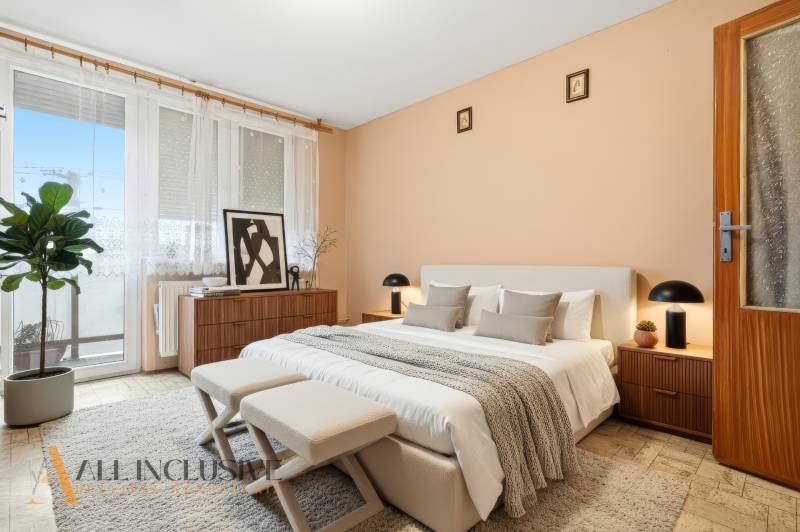 Na predaj 4-izb. rodinný dom s garážou, Okoč - Spálňa v rodinnom dome s posteľou, dekoráciami a rastlinou, svetlé steny a okno.