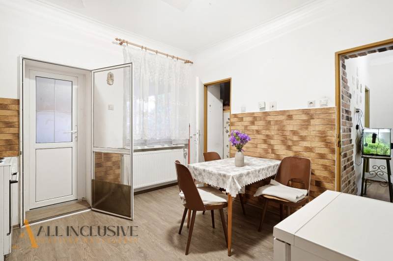 Na predaj 4-izb. rodinný dom s garážou, Okoč - Jedáleň v rodinnom dome s podlahou s dreveným dekorom a kvetmi na stole.