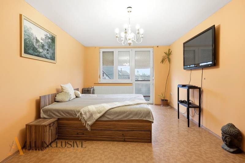 Na predaj 4-izb. rodinný dom s garážou, Okoč - Spálňa v rodinnom dome s posteľou, televízorom a podlahou s dreveným dekorom.