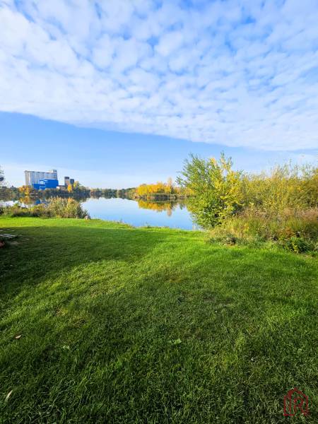 KH-1018, PREDAJ Pozemok pri jazere 887 m², garáž, altánok - Trávnatá plocha a vodná plocha obklopená vegetáciou v Čani. Výstavba domov.