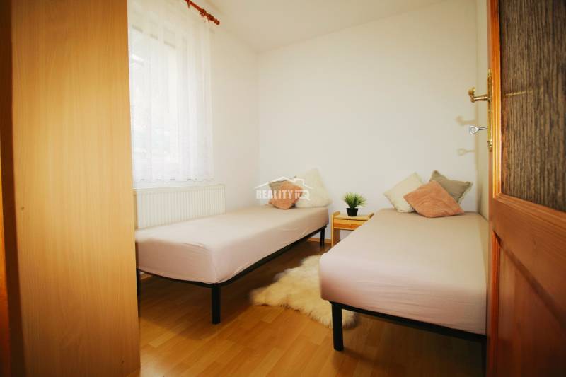 EXKLUZÍVNE / RODINNÝ DOM NA PREDAJ V OBCI SÚĽOV - Izba s dvoma posteľami, dekoratívnymi vankúšmi a podlahou s dreveným dekorom v rodinnom dome.