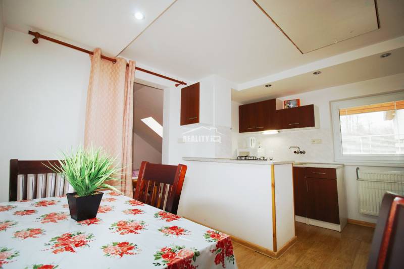 EXKLUZÍVNE / RODINNÝ DOM NA PREDAJ V OBCI SÚĽOV - Jedálenský kút s kvetinovým obrusom, kuchynským kútom a podlahou s dreveným dekorom.