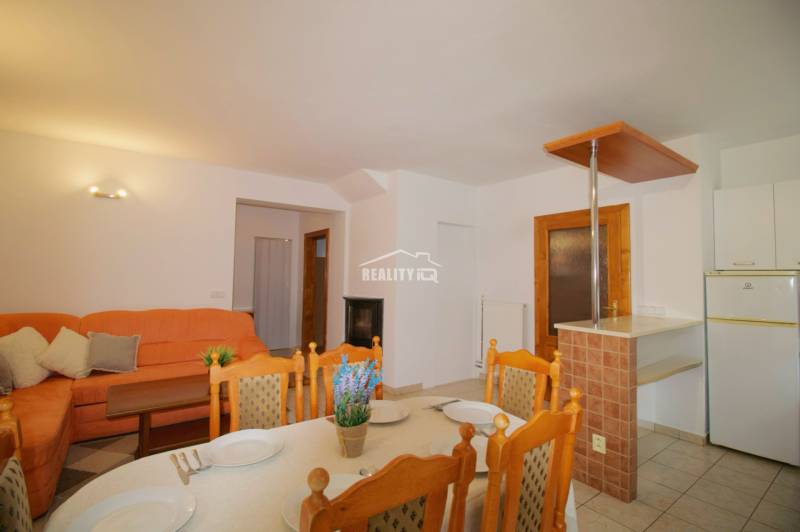 EXKLUZÍVNE / RODINNÝ DOM NA PREDAJ V OBCI SÚĽOV - Jedáleň v rodinnom dome so stolom, oranžovou pohovkou a dekoratívnymi vankúšmi.