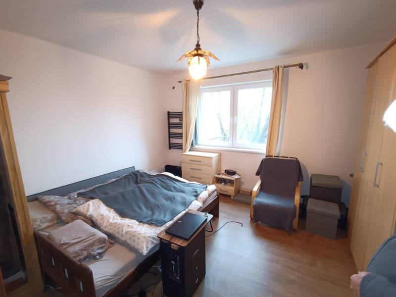 Na predaj rodinný dom Orovnica - Spálňa v rodinnom dome s posteľou, kreslom a podlahou s dreveným dekorom.