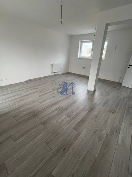 Na predaj 2 izb. byt s balkónom blízko centra, Chorvátsky Grob - Prázdna izba s podlahou s dreveným dekorom v 2-izbovom byte, biele steny, dve okná.