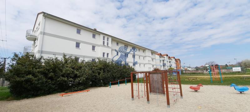 Na predaj 2 izb. byt s balkónom blízko centra, Chorvátsky Grob - Bytovky na Školskej ulici v Chorvátskom Grobe s detským ihriskom v popredí.