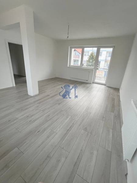 Na predaj 2 izb. byt s balkónom blízko centra, Chorvátsky Grob - Obývacia miestnosť v 2-izbovom byte s podlahou s dreveným dekorom a veľkými oknami.