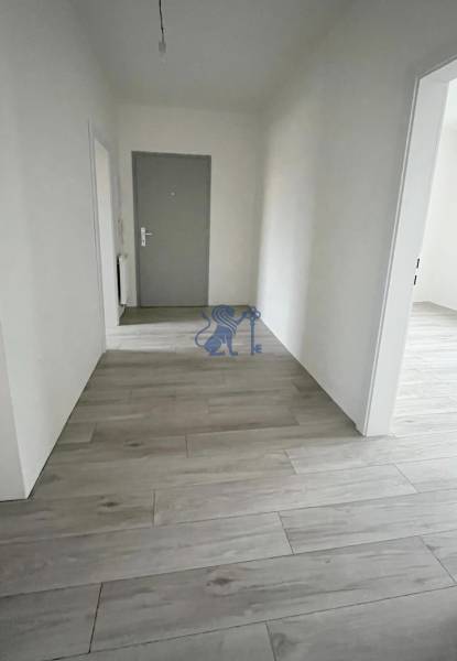 Na predaj 2 izb. byt s balkónom blízko centra, Chorvátsky Grob - Chodba v 2-izbovom byte s podlahou s dreveným dekorom, biele steny, sivé dvere.