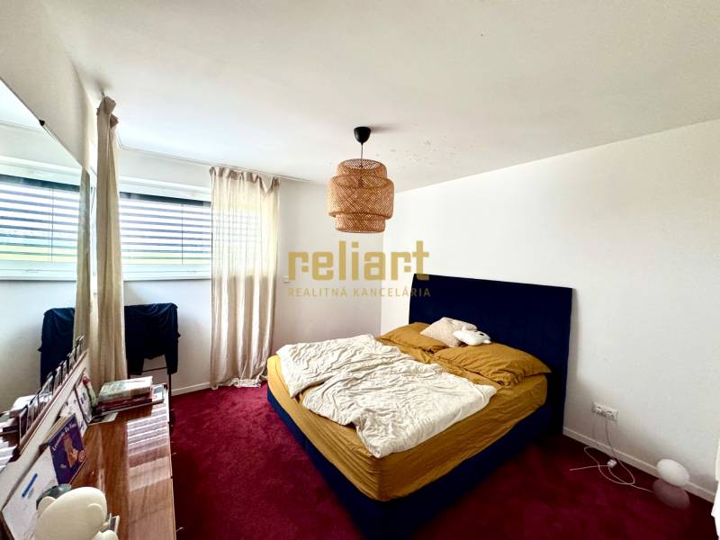 Moderný radový rodinný dom v Novej Dedinke, projekt “Lastovičky” - Spálňa v rodinnom dome s červeným kobercom, modrou posteľou a veľkým oknom.