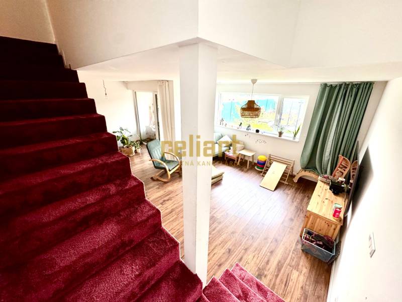 Moderný radový rodinný dom v Novej Dedinke, projekt “Lastovičky” - Interiér rodinného domu so schodiskom a obývačkou s podlahou s dreveným dekorom.