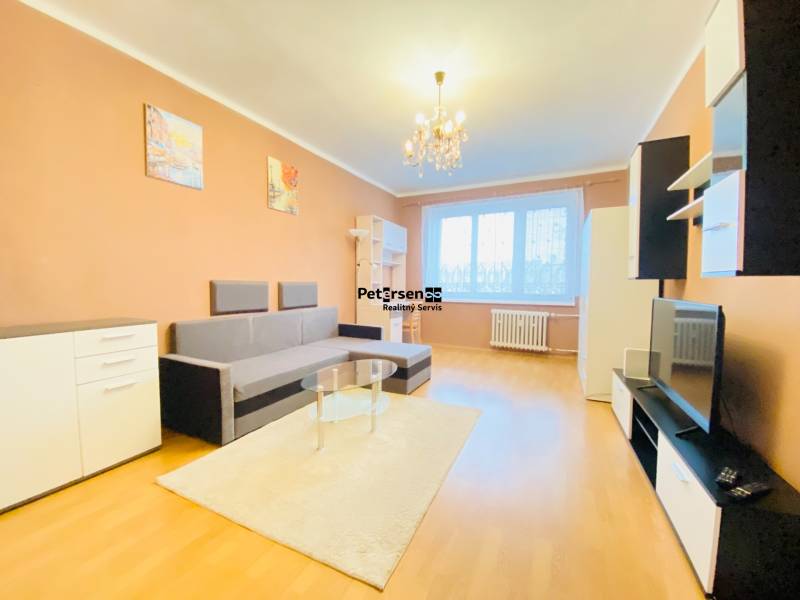 NA PRENÁJOM 2-IZBOVÝ BYT, NÁRODNÁ TRIEDA - Obývacia izba v 2-izbovom byte s podlahou s dreveným dekorom, sedačka, nábytok, luster.