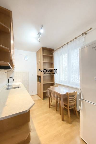NA PRENÁJOM 2-IZBOVÝ BYT, NÁRODNÁ TRIEDA - Kuchyňa v 2-izbovom byte s podlahou s dreveným dekorom, jednoduchý nábytok a spotrebiče.