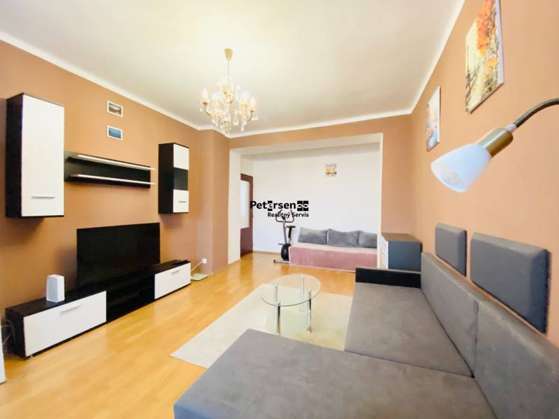 NA PRENÁJOM 2-IZBOVÝ BYT, NÁRODNÁ TRIEDA - Obývačka v 2-izbovom byte s podlahou s dreveným dekorom a pohodlnou sedačkou.