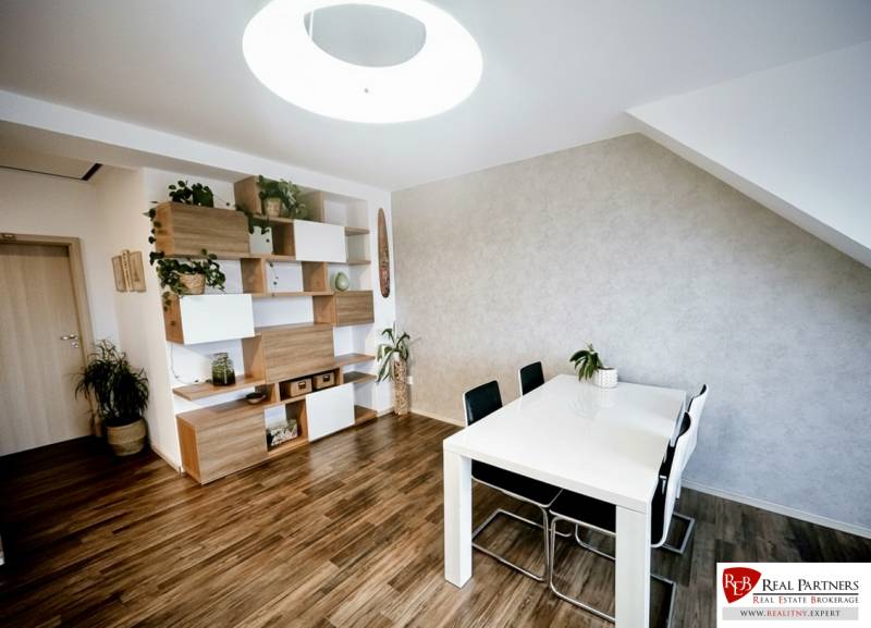 Prenájom moderný a svetlý 3-izbový byt v atraktívnej lokalite - Jedálenský stôl, stoličky a police s dekoračnými prvkami v 3-izbovom byte s podlahou s dreveným dekorom.