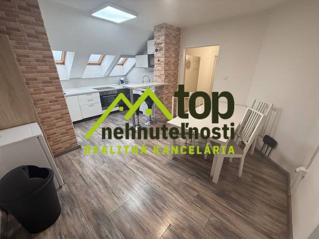 TOPOĽČANY Priestranný 1-izbový byt na prenájom 60 m2 - Kuchyňa v 1-izbovom byte s podlahou s dreveným dekorom a šikmými strešnými oknami.