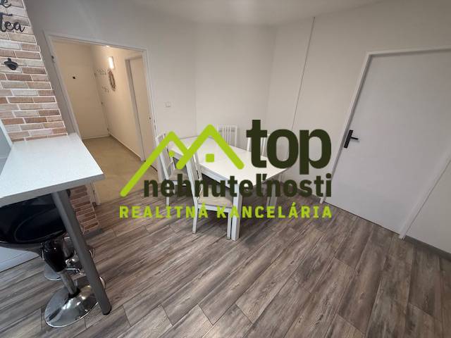TOPOĽČANY Priestranný 1-izbový byt na prenájom 60 m2 - Jedálenský kút v 1-izbovom byte s podlahou s dreveným dekorom a barovou stoličkou.