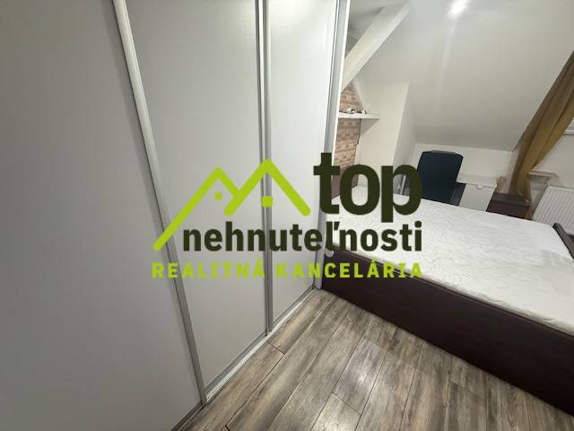TOPOĽČANY Priestranný 1-izbový byt na prenájom 60 m2 - Spálňa v 1-izbovom byte s podlahou s dreveným dekorom a vstavanou skriňou.