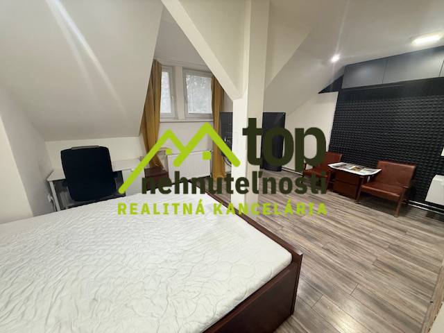 TOPOĽČANY Priestranný 1-izbový byt na prenájom 60 m2 - Spálňa v 1-izbovom byte s podlahou s dreveným dekorom a nábytkom.