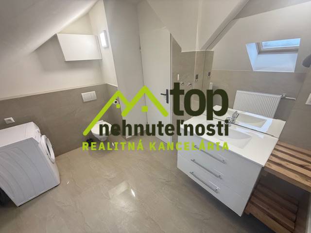 TOPOĽČANY Priestranný 1-izbový byt na prenájom 60 m2 - Kúpeľňa s práčkou v 1-izbovom byte, svetlé farby, podlaha s dreveným dekorom.