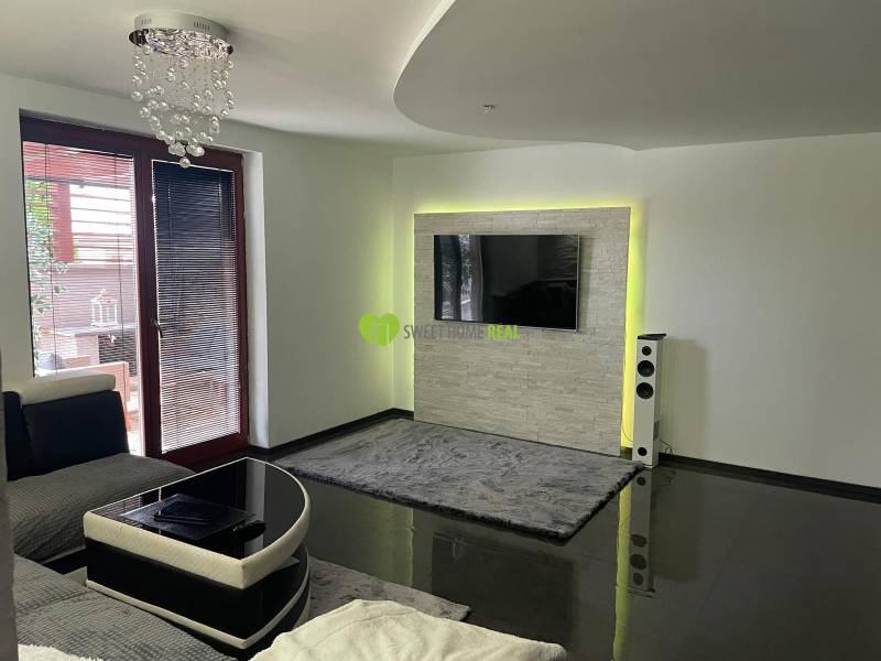Moderný zariadený rodinný dom na prenájom 120m2 s terasou Košice Barca - Obývacia izba v rodinnom dome s lesklou podlahou a TV na stene.
