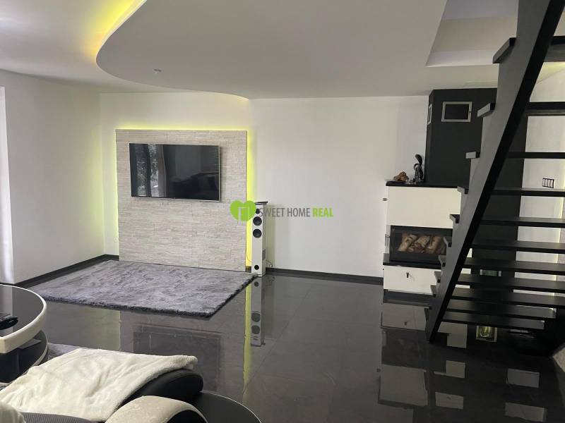 Moderný zariadený rodinný dom na prenájom 120m2 s terasou Košice Barca - Obývacia izba v rodinnom dome so schodiskom, krbom a televíziou na stene.