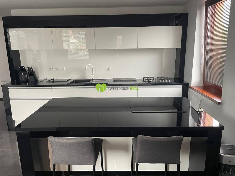 Moderný zariadený rodinný dom na prenájom 120m2 s terasou Košice Barca - Kuchyňa v rodinnom dome s lesklým čierno-bielym nábytkom a jedálenským pultom.