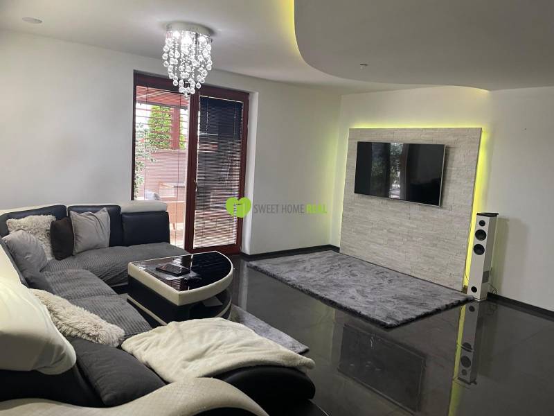 Moderný zariadený rodinný dom na prenájom 120m2 s terasou Košice Barca - Obývačka v rodinnom dome so sedačkou a televízorom na stene s kamenným obkladom.