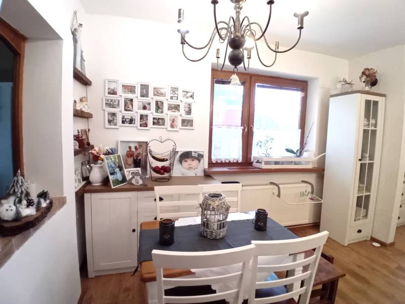 Rodinný dom, Vršatské Podhradie, okres Ilava - Jedáleň v rodinnom dome s bielym nábytkom, obrázkami na stene a ozdobným lustrom.