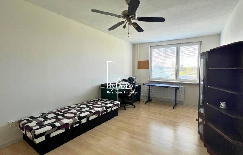 3-izbový byt na prenájom, 87 m2, Beethovenova ul. Nitra - Izba v 3-izbovom byte s posteľou, stolom a podlahou s dreveným dekorom.