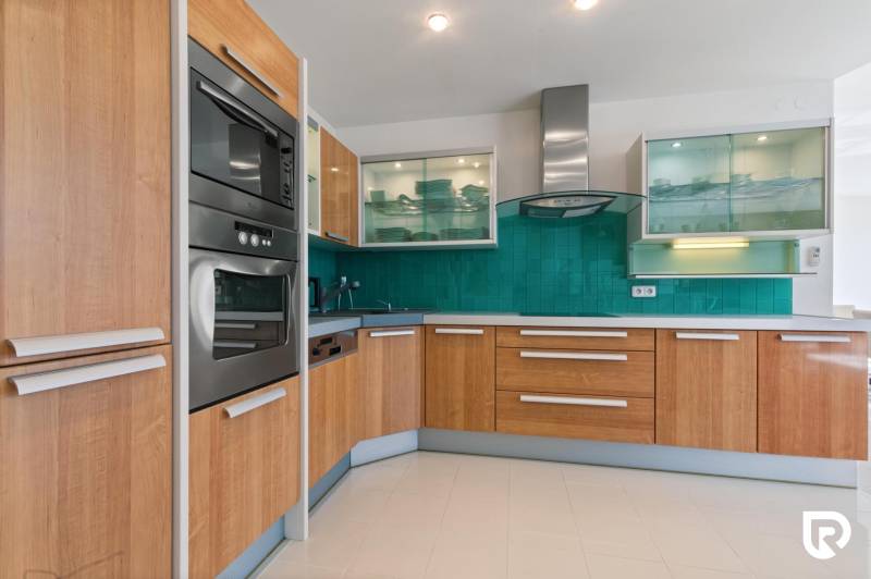 Staré Mesto | 5i byt 175 m² + 4 balkóny + možnosť 2× parking - Kuchyňa s chladničkou, rúrou, podlahou s dreveným dekorom a zeleným obkladom v 5 izbovom byte.