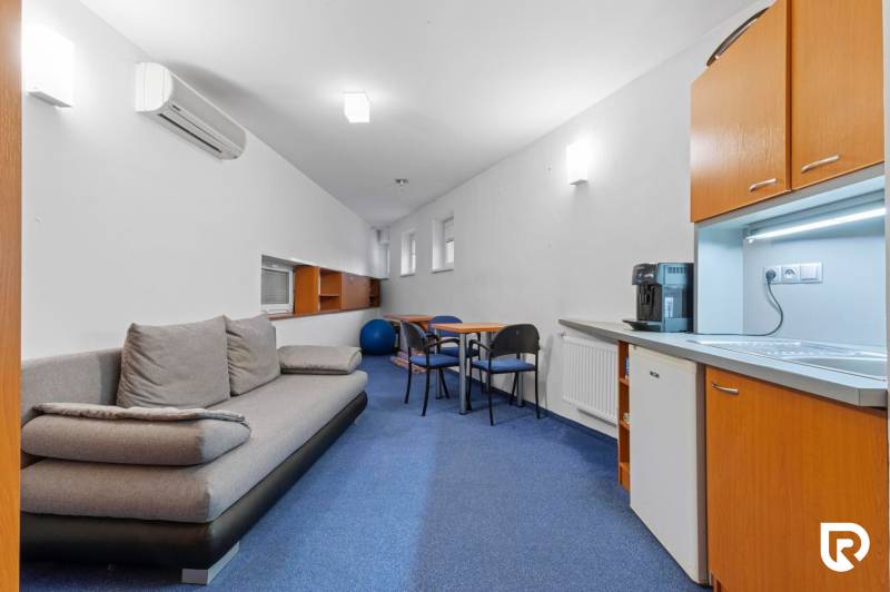 Kancelárie-Showroom 357 m², Zadunajská cesta, Petržalka, BA - Kancelárie so sivou pohovkou, modrým kobercom, kuchynskou linkou a kávovarom.