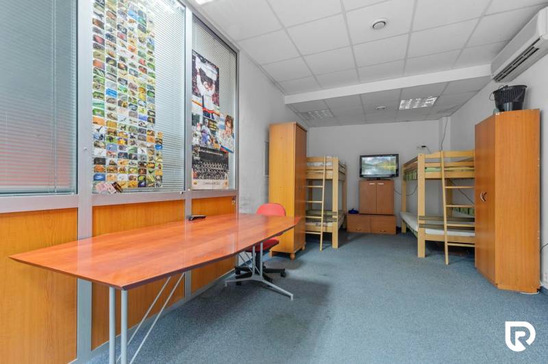 Kancelárie-Showroom 357 m², Zadunajská cesta, Petržalka, BA - Interiér obchodných priestorov s poschodovými posteľami, stolom a televízorom na stene.