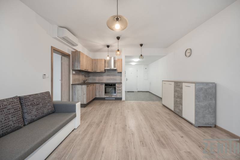 PREDAJ 2-IZBOVÉHO BYTU – NOVOSTAVBA JARABINKY, RUŽINOV - Obývacia izba s kuchyňou a podlahou s dreveným dekorom v 2-izbovom byte.