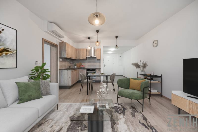 PREDAJ 2-IZBOVÉHO BYTU – NOVOSTAVBA JARABINKY, RUŽINOV - Obývacia izba s kuchynským kútom v 2-izbovom byte s podlahou s dreveným dekorom a pohodlným sedením.