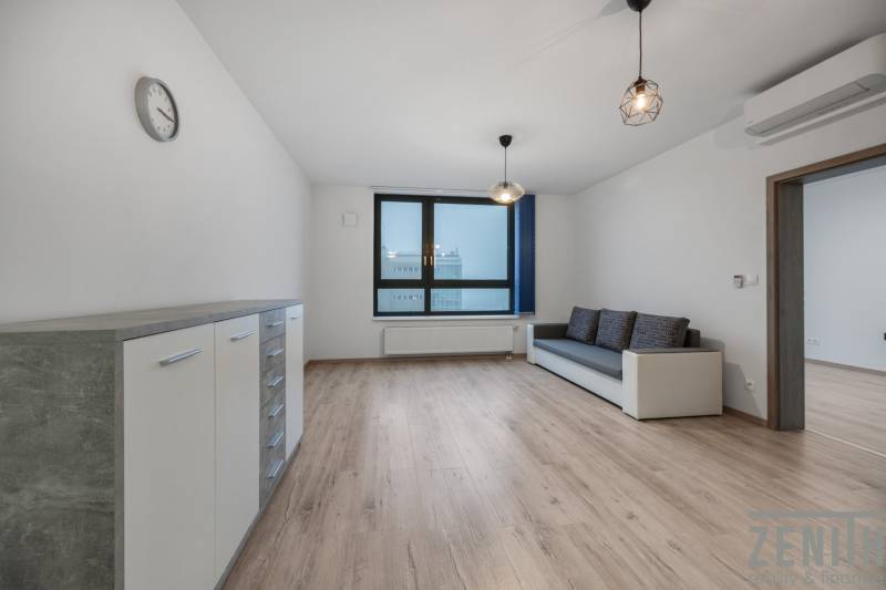 PREDAJ 2-IZBOVÉHO BYTU – NOVOSTAVBA JARABINKY, RUŽINOV - Obývacia izba v 2-izbovom byte s pohovkou a podlahou s dreveným dekorom.