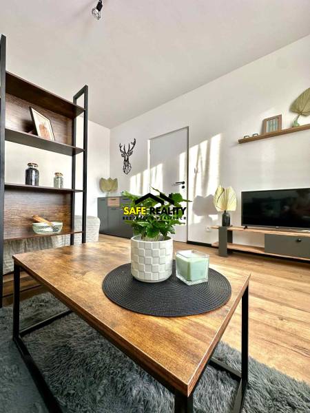 REZERVOVANÝ PREDAJ 1-izbový byt, Vlčince - okr. Žilina - Obývacia izba v 1-izbovom byte s podlahou s dreveným dekorom a dekoráciami.