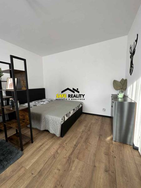 REZERVOVANÝ PREDAJ 1-izbový byt, Vlčince - okr. Žilina - Spálňa v 1-izbovom byte s podlahou s dreveným dekorom a minimalistickým zariadením.