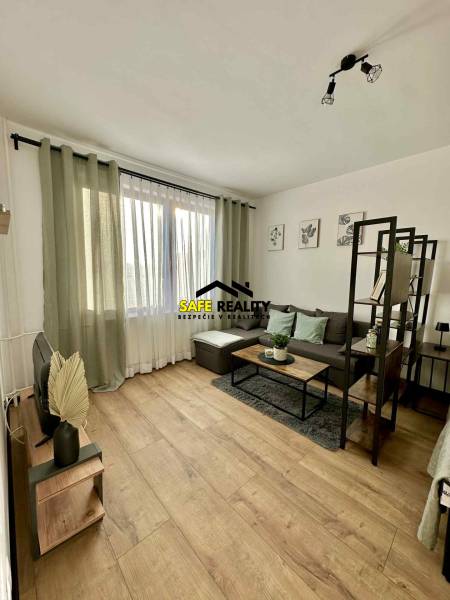 REZERVOVANÝ PREDAJ 1-izbový byt, Vlčince - okr. Žilina - Interiér 1-izbového bytu s pohovkou, stolíkom a podlahou s dreveným dekorom.