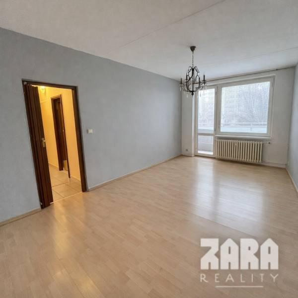 LUDMANSKÁ - 3 izbový byt, 65 m2 + loggia. KÚPOU VOĽNÝ. ČR. - Izba s podlahou s dreveným dekorom a lustrom v 3-izbovom byte.