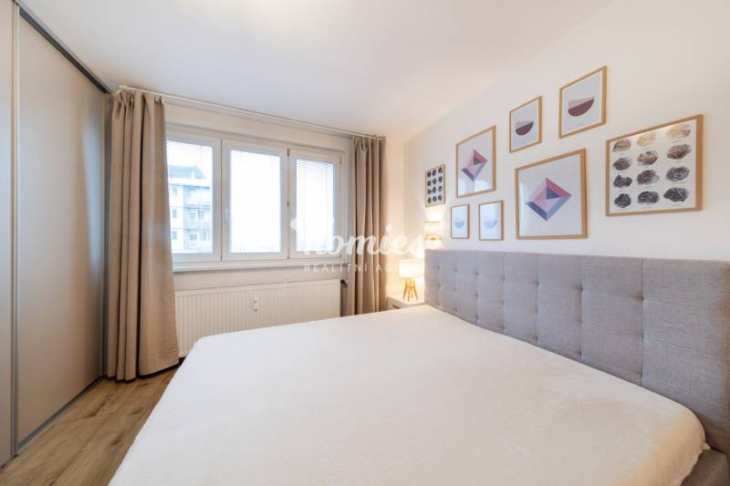 PREDAJ 2 izbový moderne zrekonštruovaný byt s klimatizáciou, CENTRUM - Svetlá spálňa s podlahou s dreveným dekorom, posteľou a nástennými obrazmi v 2-izbovom byte.