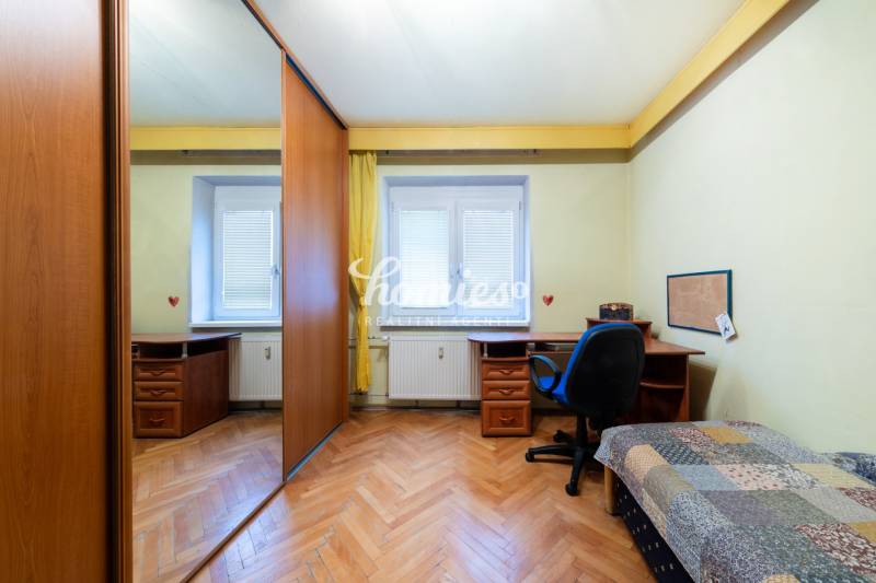 NA PREDAJ 3-izbový byt v centre, jedinečný výhľad na mesto, Nitra - Izba s podlahou s dreveným dekorom, stolom a skriňou v 3-izbovom byte.