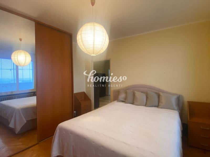 NA PREDAJ 3-izbový byt v centre, jedinečný výhľad na mesto, Nitra - Spálňa v 3-izbovom byte so skriňou, posteľou a podlahou s dreveným dekorom.