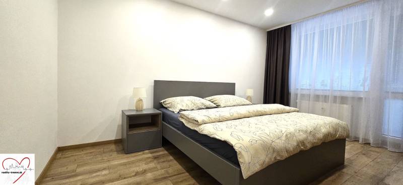 Prenájom komfortný, zariadený 3 izbový byt po úplnej rekonštrukcii - Spálňa s posteľou, nočným stolíkom a podlahou s dreveným dekorom v 3-izbovom byte.