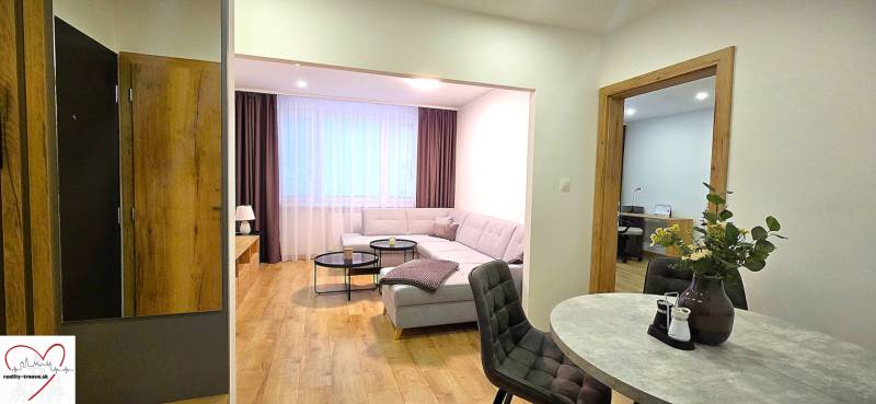 Prenájom komfortný, zariadený 3 izbový byt po úplnej rekonštrukcii - Obývacia izba 3-izbového bytu so sedačkou, stolíkom a podlahou s dreveným dekorom.