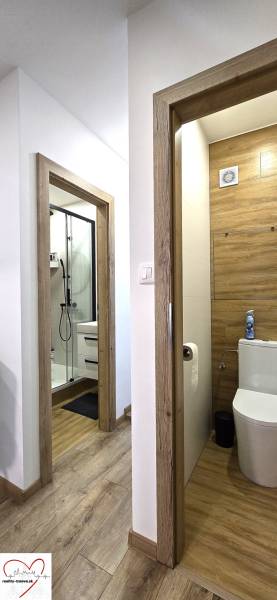 Prenájom komfortný, zariadený 3 izbový byt po úplnej rekonštrukcii - Chodba s podlahou s dreveným dekorom, dve miestnosti, kúpeľňa a toaleta v 3-izbovom byte.