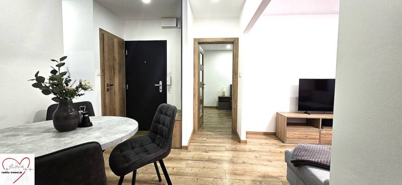 Prenájom komfortný, zariadený 3 izbový byt po úplnej rekonštrukcii - Interiér 3-izbového bytu s podlahou s dreveným dekorom a štýlovým stolom.