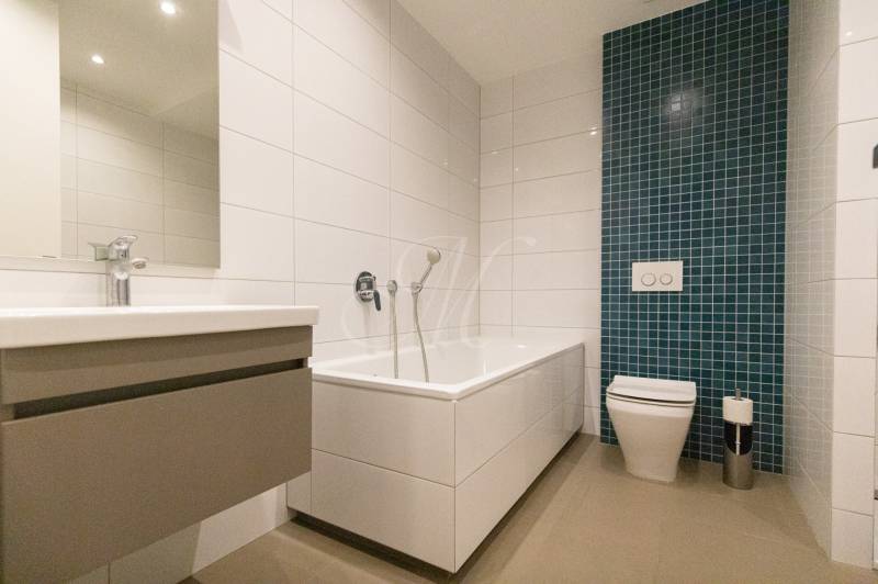 Exkluzívny 2i byt s terasou a parkovaním, Kramáre - Kúpeľňa v 2-izbovom byte s vaňou, umývadlom a zeleným obkladačkovým panelom.