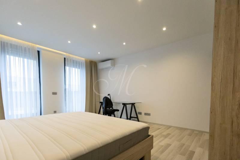 Exkluzívny 2i byt s terasou a parkovaním, Kramáre - Spálňa v 2-izbovom byte s posteľou, stolom a podlahou s dreveným dekorom.