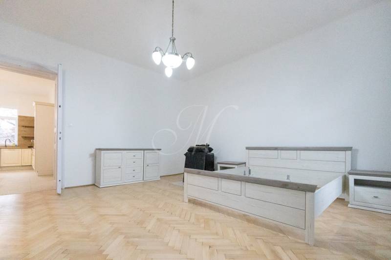 Priestranný 3i byt s vysokými stropmi, Dunajská - Spálňa s posteľou, nábytkom a podlahou s dreveným dekorom v 3-izbovom byte.